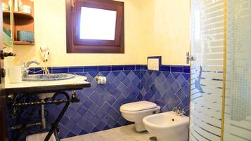 A bathroom with a sink, two toilets, and a window.