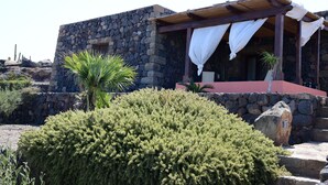 A stone building with a covered porch and a red roof. - Dammusi Sotto le Stelle (Pantelleria)