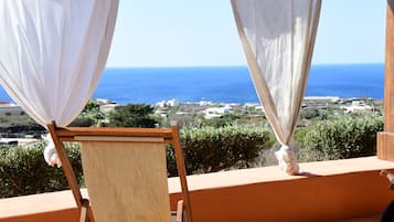 A balcony with a view of the sea, a wooden easel, and a white curtain.