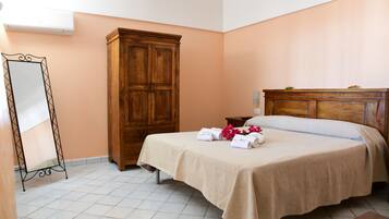 Quarto com cama, guarda-roupa de madeira, espelho e chão em azulejos.