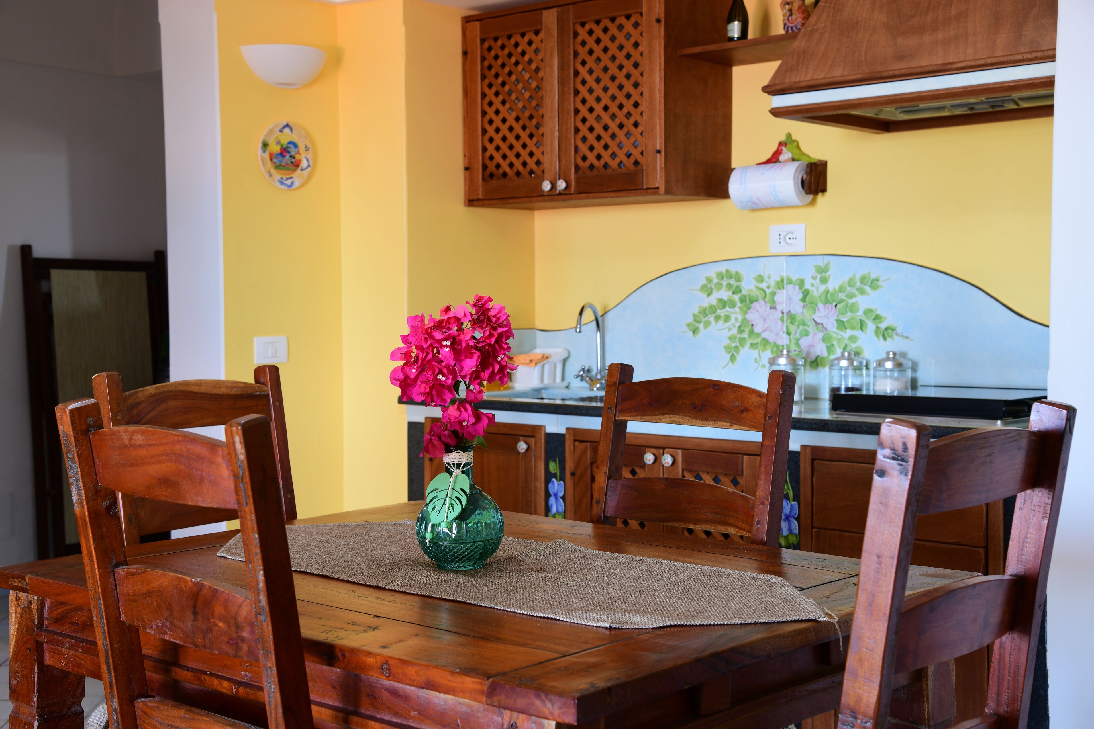 Una mesa de comedor de madera con un florero, rodeada de sillas de madera.