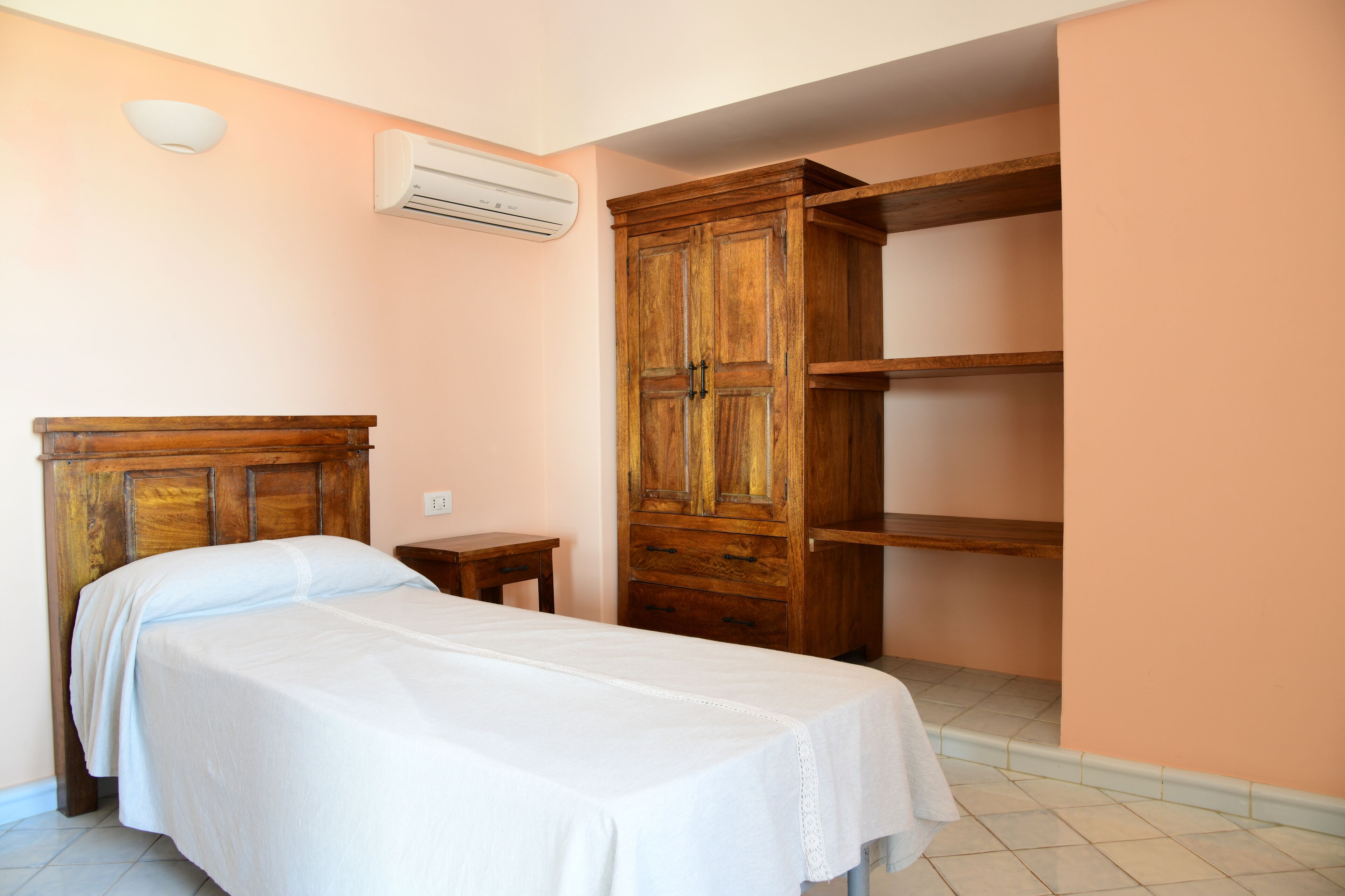 Une chambre à coucher avec un lit en bois, une armoire et une petite table de chevet.