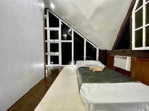A bedroom with a sloped ceiling, a large window, a bed, and a radiator. - Trail Inn - Puerto Princesa City (Puerto Princesa)