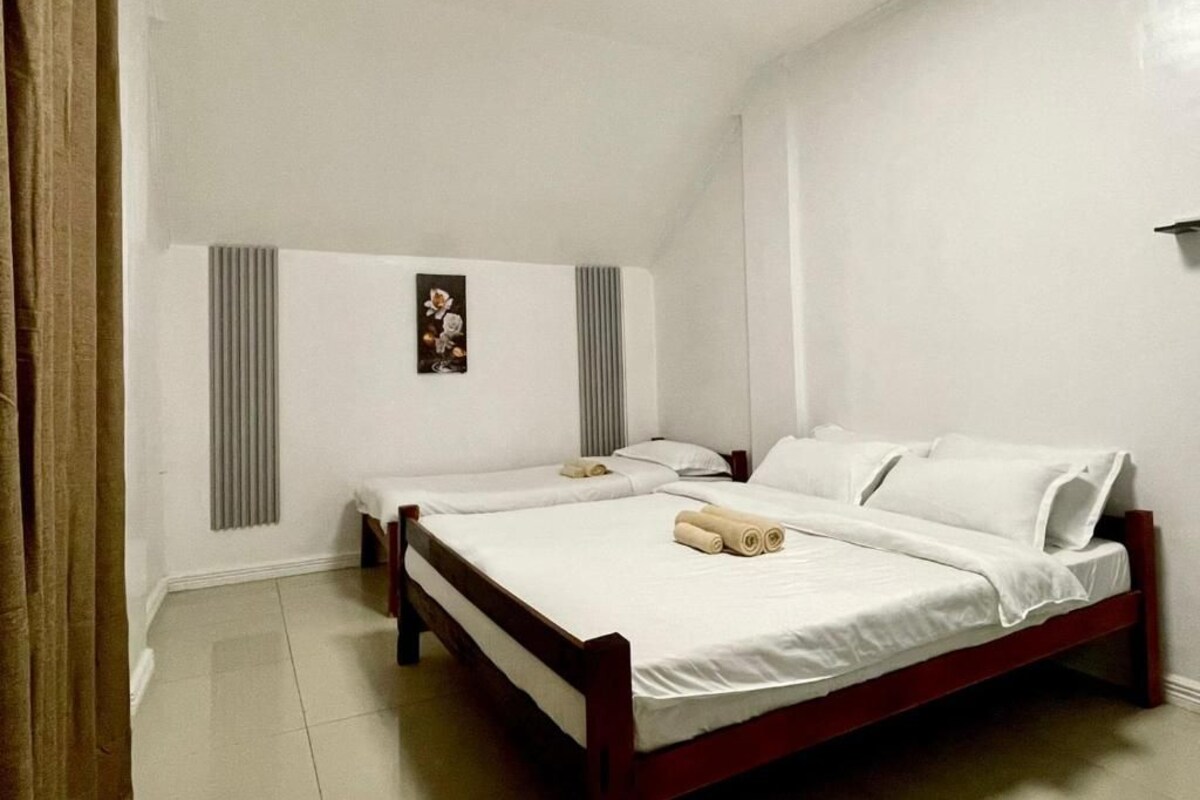A room with two single beds, a radiator, a wall-mounted picture, and a curtain.