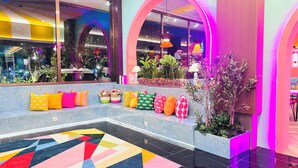A modern interior with a colorful geometric carpet, a seating area with cushions, and a variety of plants. - Yellow Bee Resort Cililitan  (Jakarta)