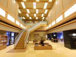 A spacious lobby with a central staircase, wooden flooring, and a large floral arrangement.
