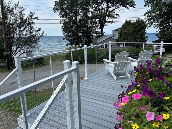 A wooden deck with white railings, a chair, and a flower planter. - North East Lake House Unit #1 with Wrap-around Deck (North East)