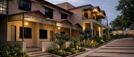 A two-story building with a balcony, steps leading to the entrance, and a well-lit exterior.