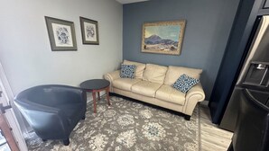 A living room with a beige sofa, two patterned pillows, a black armchair, a small round table, and a large painting on the wall. - Charming Upstairs 2-bedroom townhome W/ side entrance & Balcony in Kyle AC, WiFi (Kyle)