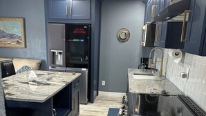 A modern kitchen with dark cabinetry, a built-in refrigerator, a stove, and a marble countertop. - Charming Upstairs 2-bedroom townhome W/ side entrance & Balcony in Kyle AC, WiFi (Kyle)