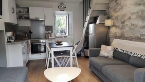 A compact living space with a kitchenette, a dining area, and a seating area with a sofa and a table.