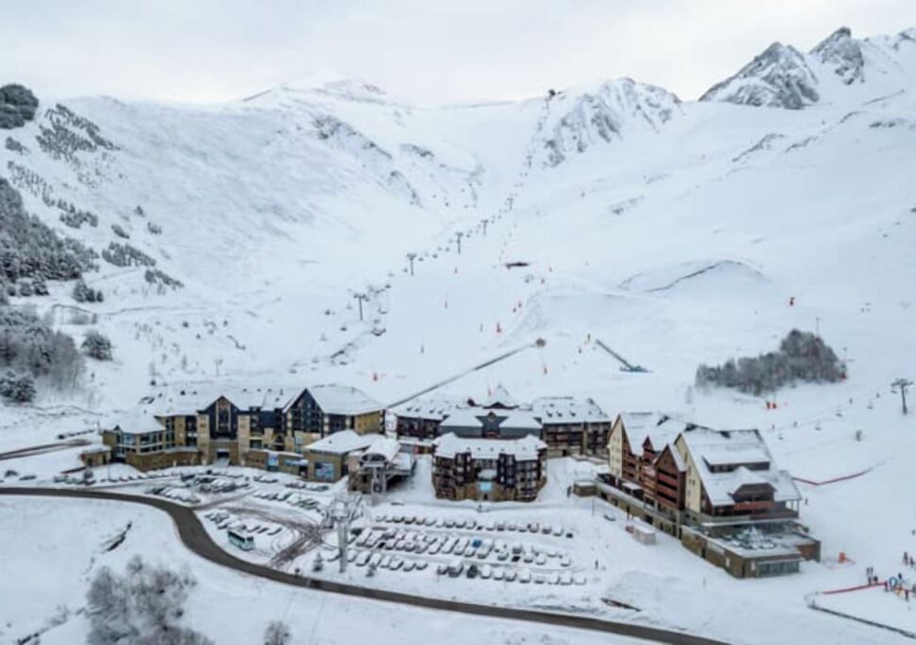 Un centro de esquí cubierto de nieve con varios edificios, incluyendo un refugio y una zona de teleférico.