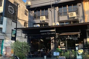 A hostel cafe with outdoor seating, air conditioning units, and a signboard. - Friends Station Hostel & Cafe (Pattaya)