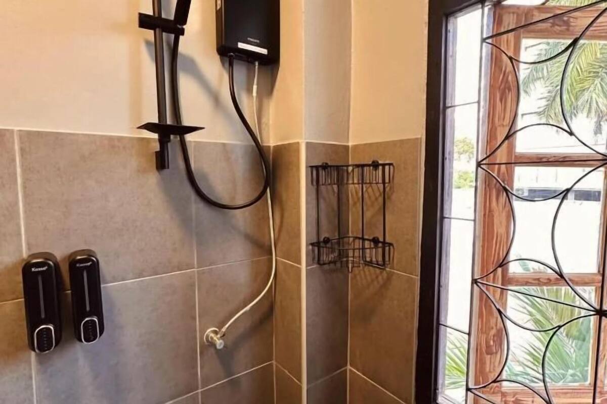 A bathroom with a shower, a towel rack, and a window with a decorative metal frame.