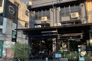 A hostel cafe with outdoor seating, air conditioning units, and a signboard. - Friends Station Hostel & Cafe (Pattaya)