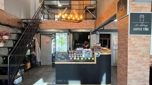 A coffee shop with a counter, a staircase, and a sign that says "it's always coffee time." - Friends Station Hostel & Cafe (Pattaya)