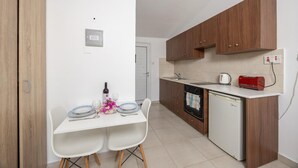 Una cocina compacta con armarios de madera, una encimera blanca, horno empotrado y lavavajillas pequeño.