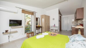 Habitación de hotel con cama, televisión, escritorio y kitchenette.