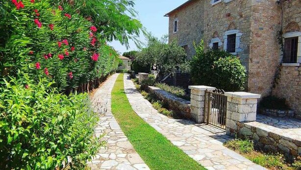 Un edificio de piedra con un camino de piedra que lleva a una entrada portonada.