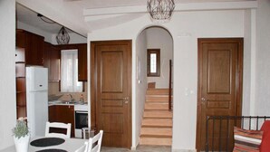 Un espacio habitable compacto con cocina, comedor y una escalera que sube a un segundo piso.