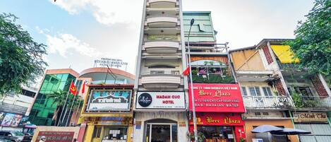 Un hotel con un letrero que dice "MADAM QUC HOTEL" y una fachada con un anuncio de "Beer Plaza".