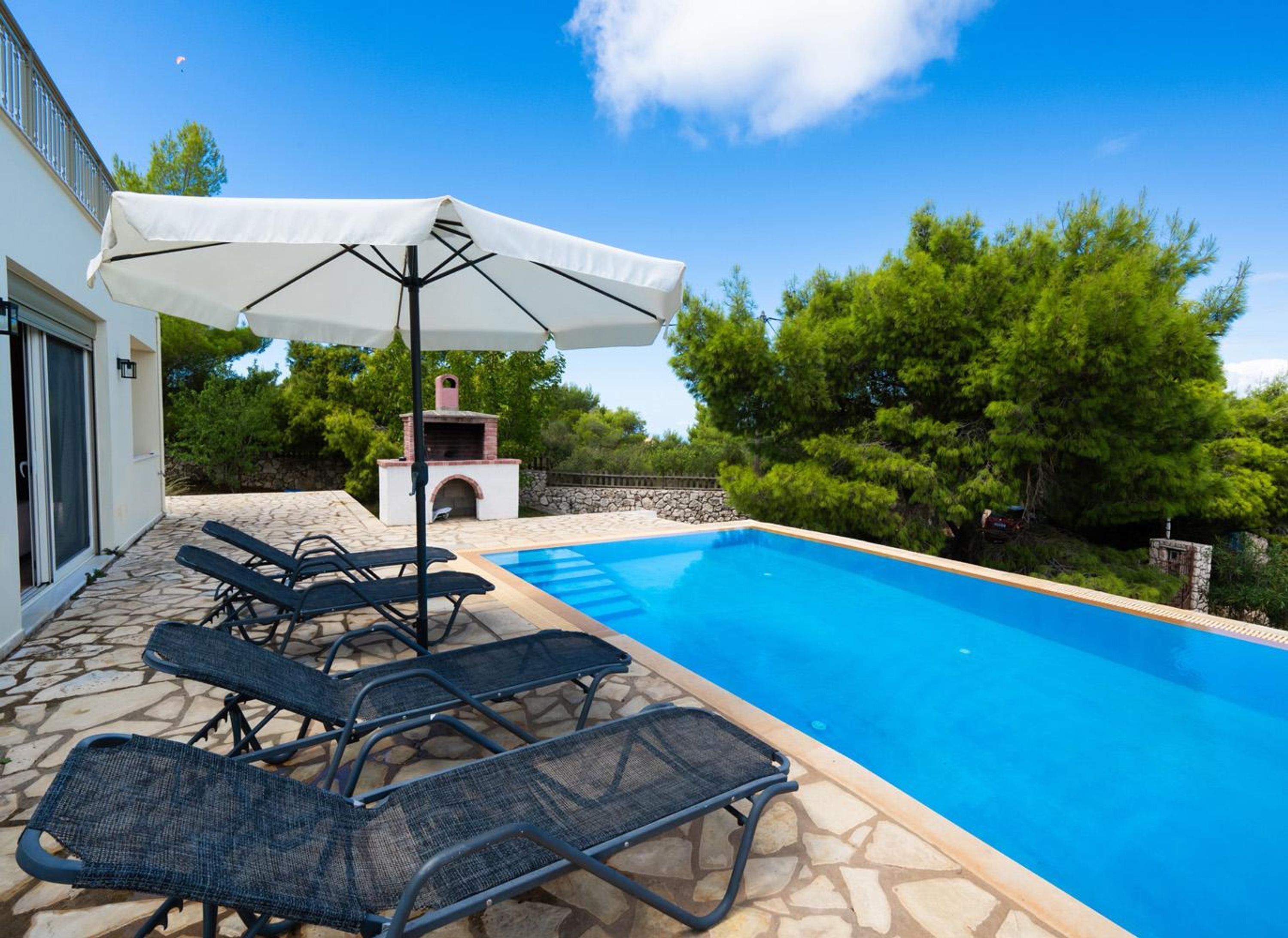 A swimming pool with lounge chairs and a barbecue area.
