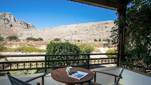A wooden table with a magazine and a cup, set against a mountainous backdrop. - Villa Driftwood in Rhodes (Rhodes)