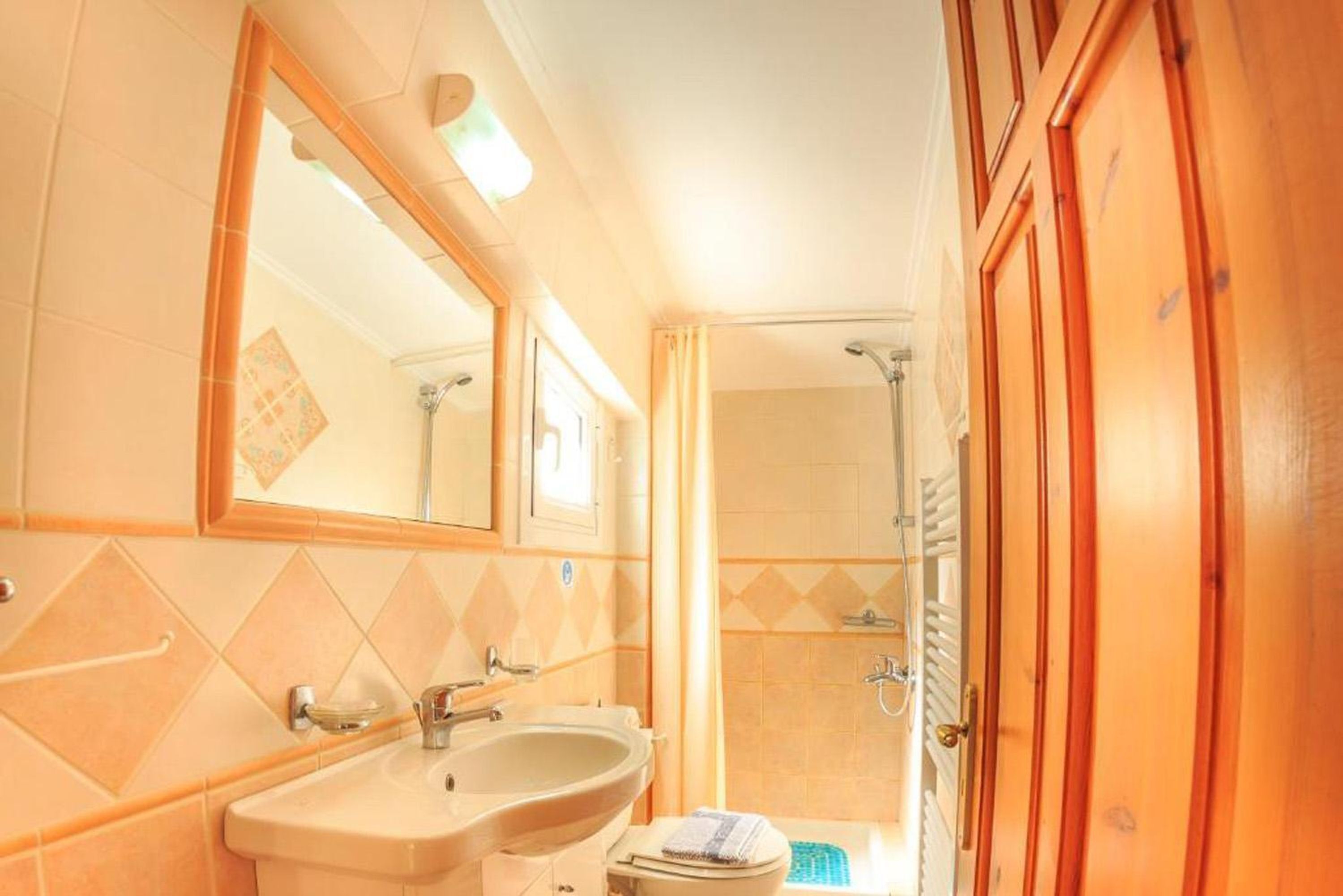 A bathroom with a sink, mirror, shower, and wooden door.