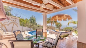 A covered outdoor area with a pool, dining table, and chairs, overlooking a scenic landscape. - Villa Buenavista in C Mpeta (Torrox)