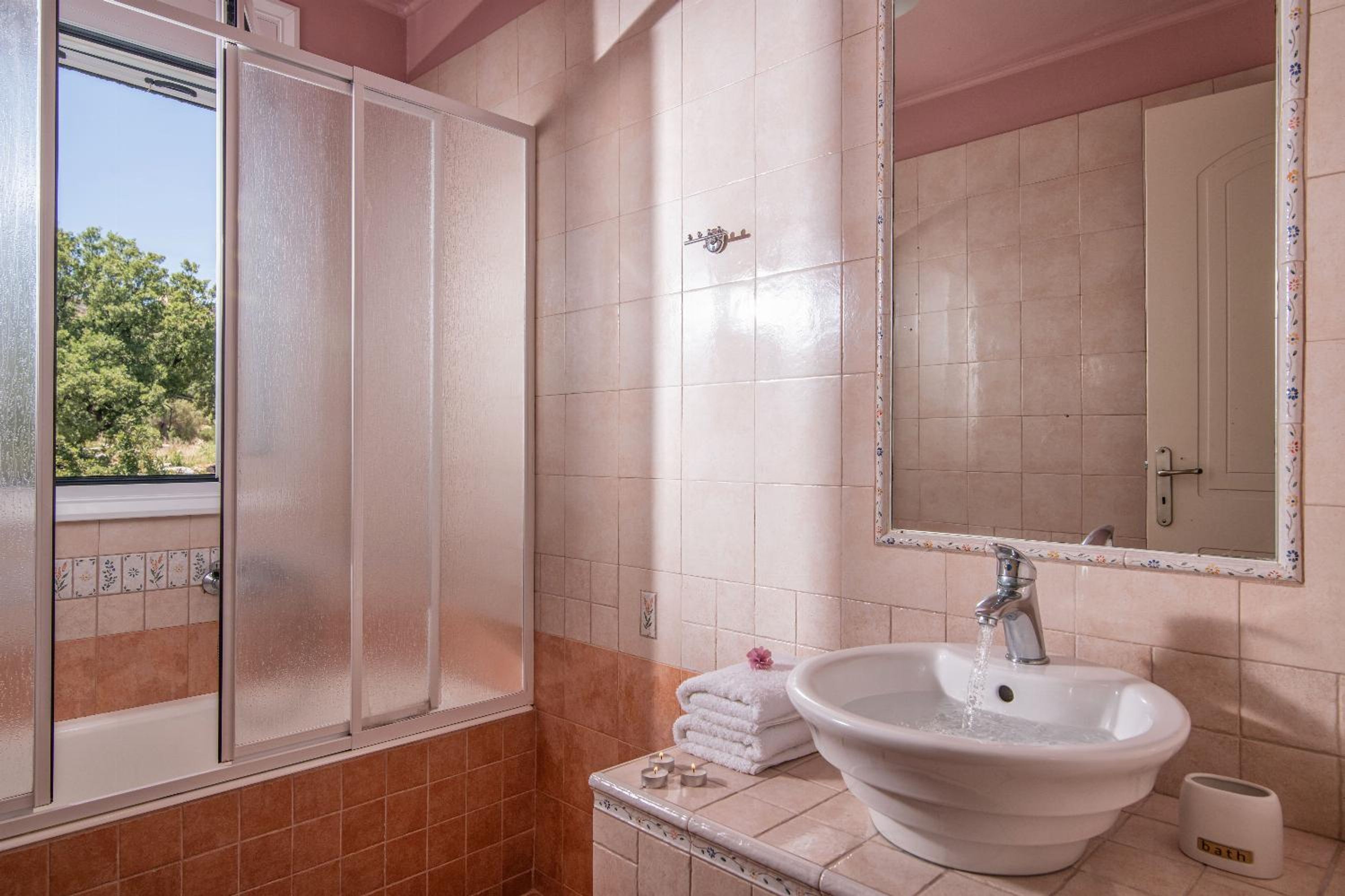 A bathroom with a large mirror, a sink, and a shower with frosted glass doors.