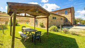 A rustic stone house with a wooden pergola and picnic table in the backyard. - Casale del Conte in Pienza (Sarteano)