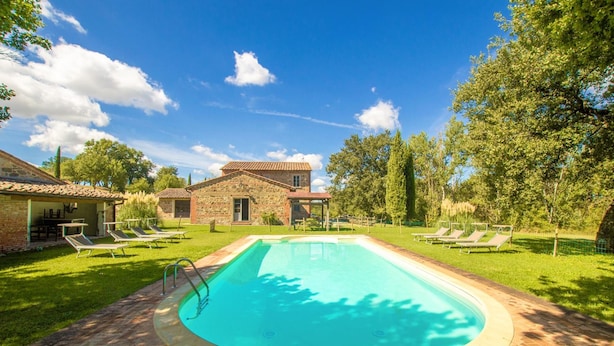 A swimming pool with lounge chairs, a stone building, and a grassy area. - Casale del Conte in Pienza (Sarteano)