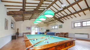A pool table in a room with wooden beams and green pendant lights. - Casale del Conte in Pienza (Sarteano)