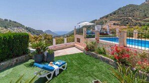 Un espace piscine privé offrant une vue sur la mer, entouré d’un mur de pierre et d’une végétation luxuriante.
