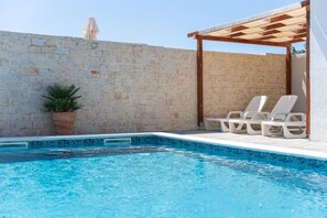 A swimming pool with a stone wall and a wooden pergola. - Villa Iva in Donje Ra Tane (Sveti Filip i Jakov)