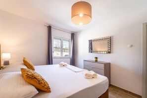 A hotel room with a bed, a bedside lamp, a dresser, a mirror, and a window with curtains. - Villa Iva in Donje Ra Tane (Sveti Filip i Jakov)
