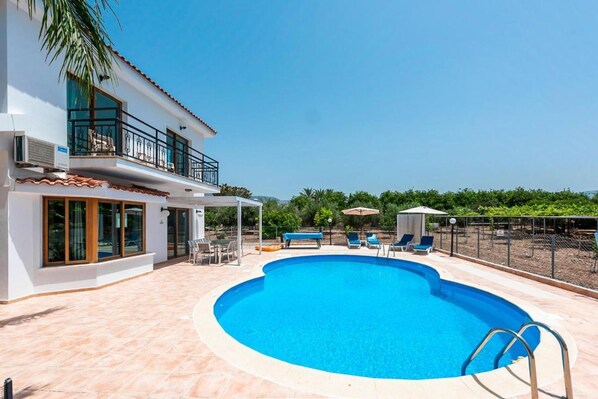 A two-story house with a swimming pool, outdoor furniture, and a covered patio area. - Villa Corallina in Peyia (Pegeia)