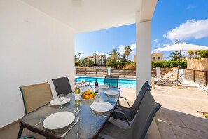 Ein Essbereich mit Tisch für vier Personen, mit Blick auf einen Pool und die umliegende Gegend.