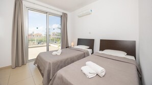 A hotel room with two beds, a balcony, and an air conditioning unit.