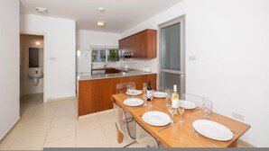 A modern kitchen with a wooden island, a dining table set for four with plates, wine glasses, and cutlery.