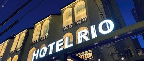 A hotel sign with the name "HOTELRIO" illuminated against a night sky.