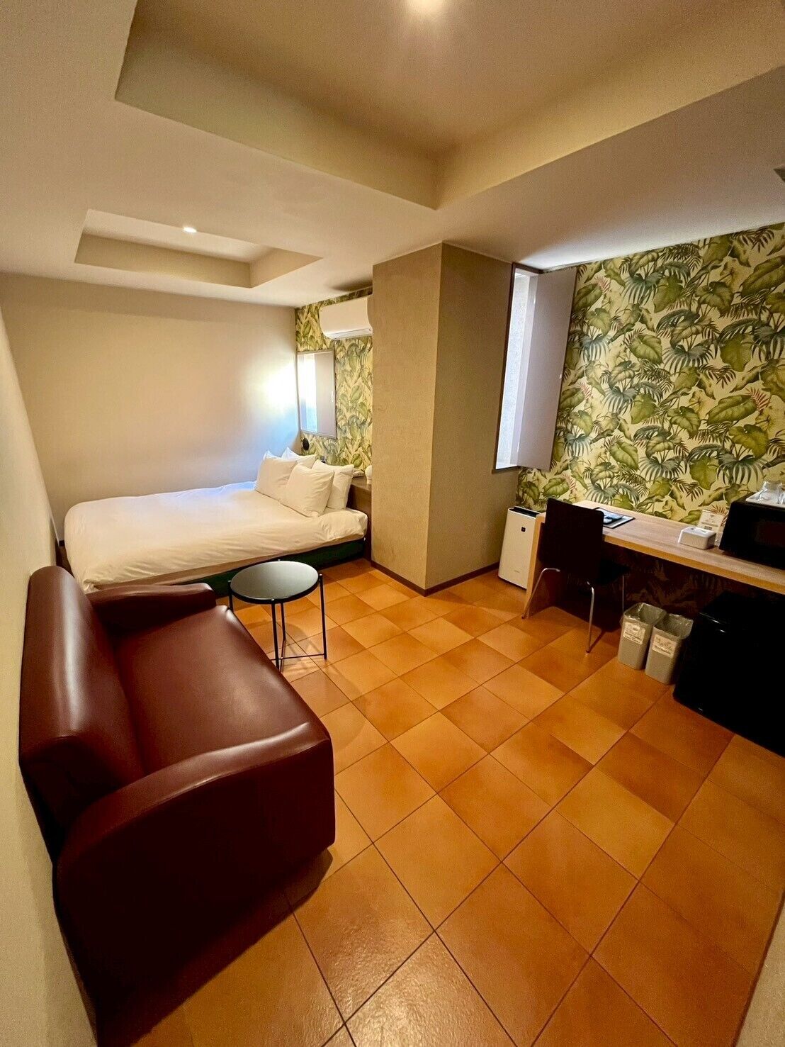 A compact room with a bed, a small desk, a chair, and a sofa.