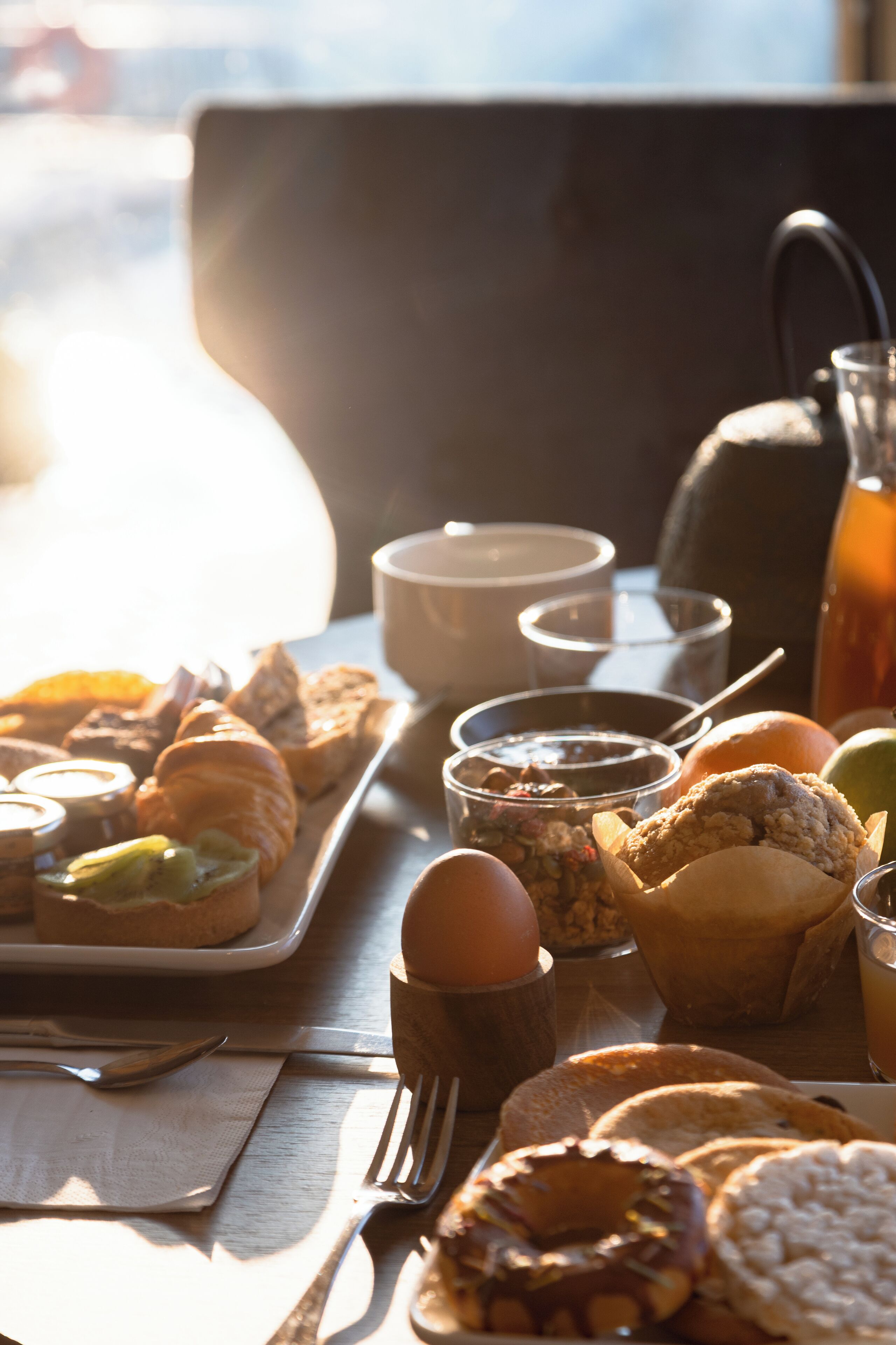 A breakfast table with pastries, a cup, and a teapot.