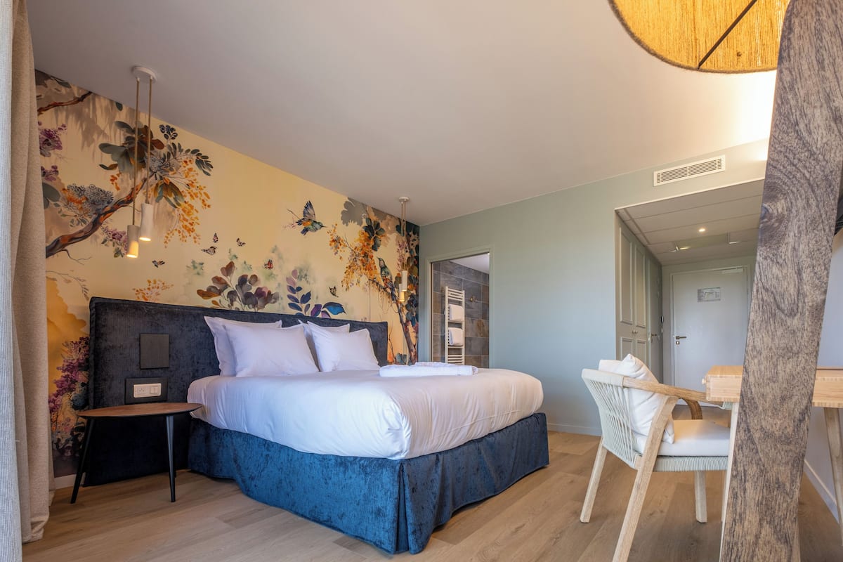 A modern bedroom with a large bed, a small table, and a chair.
