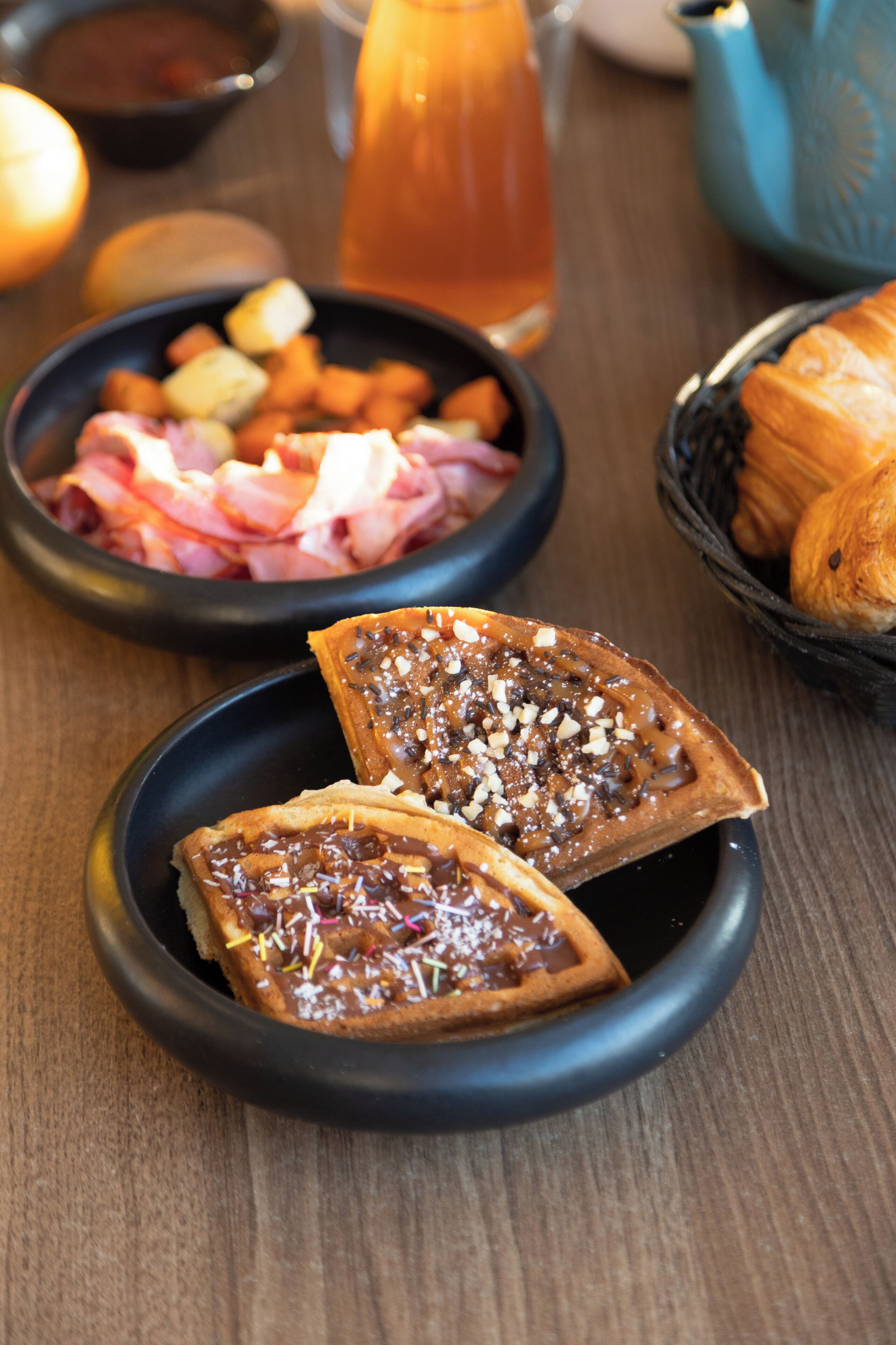 Uma mesa com uma fatia de torrada, uma tigela de carne e um cesto de croissants.