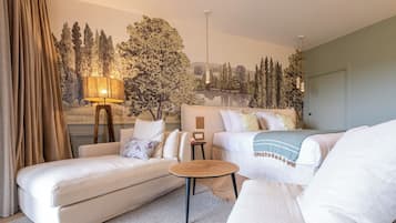 Et hotelværelse med en stor seng, en sofa, et lille bord og en lampe.