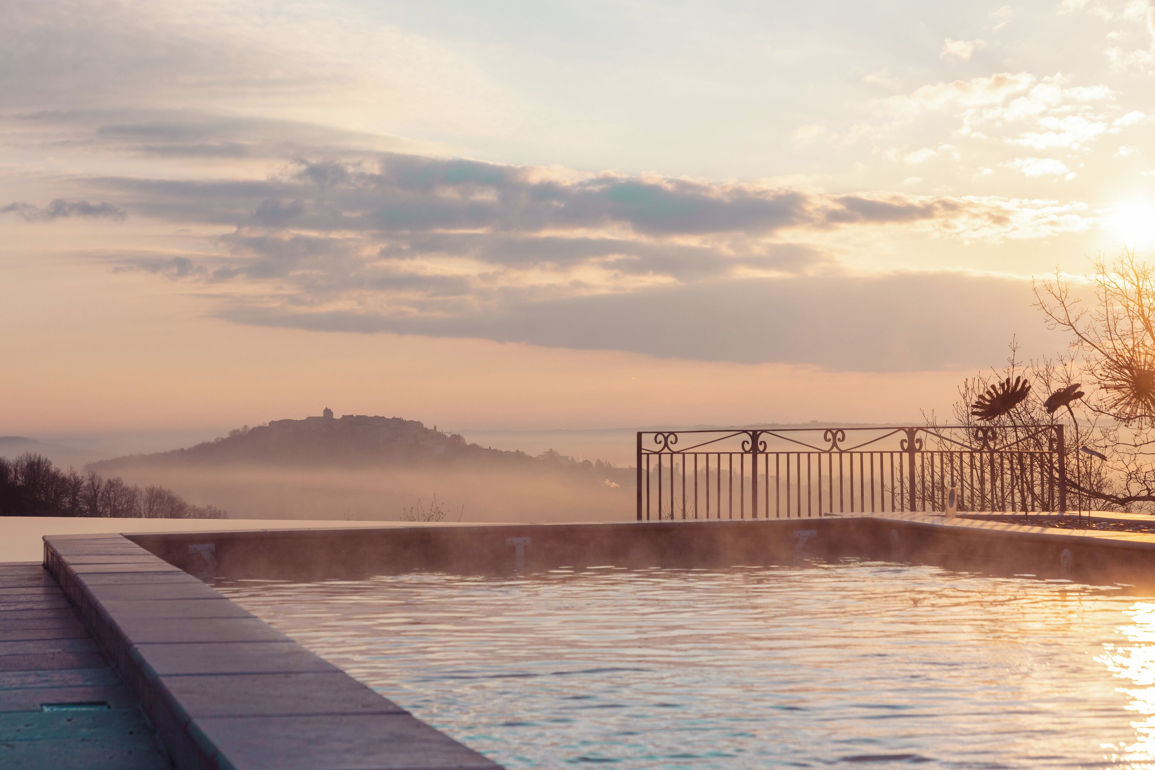 A swimming pool with a view of a distant hill and a gate.