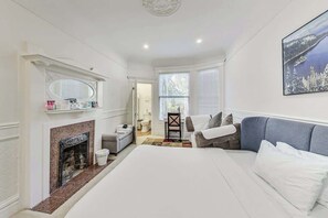 Ein Schlafzimmer mit Kamin, einem Bett, einer Couch und einem Gemälde an der Wand.
