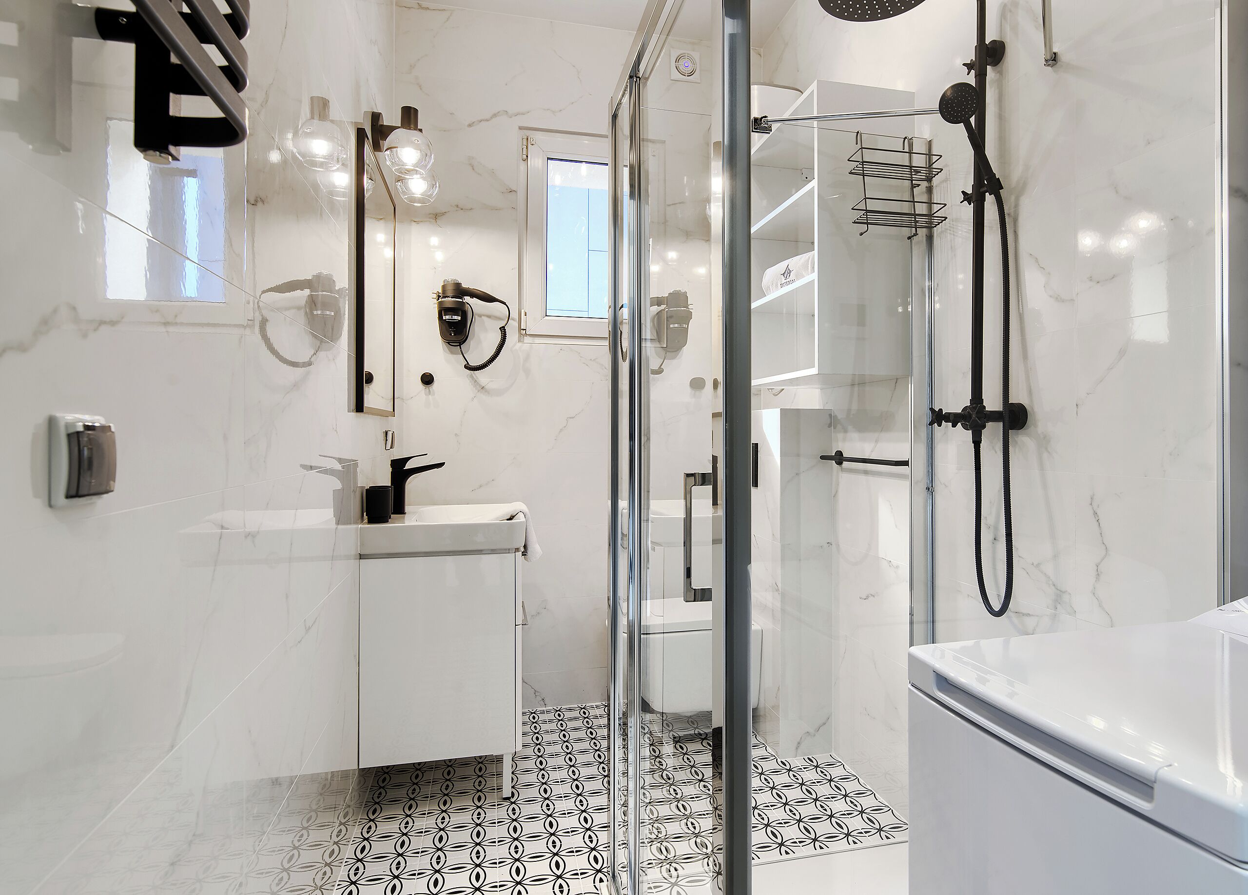 Une salle de bain moderne avec une douche à parois de verre, un lavabo blanc et un carrelage décoratif.
