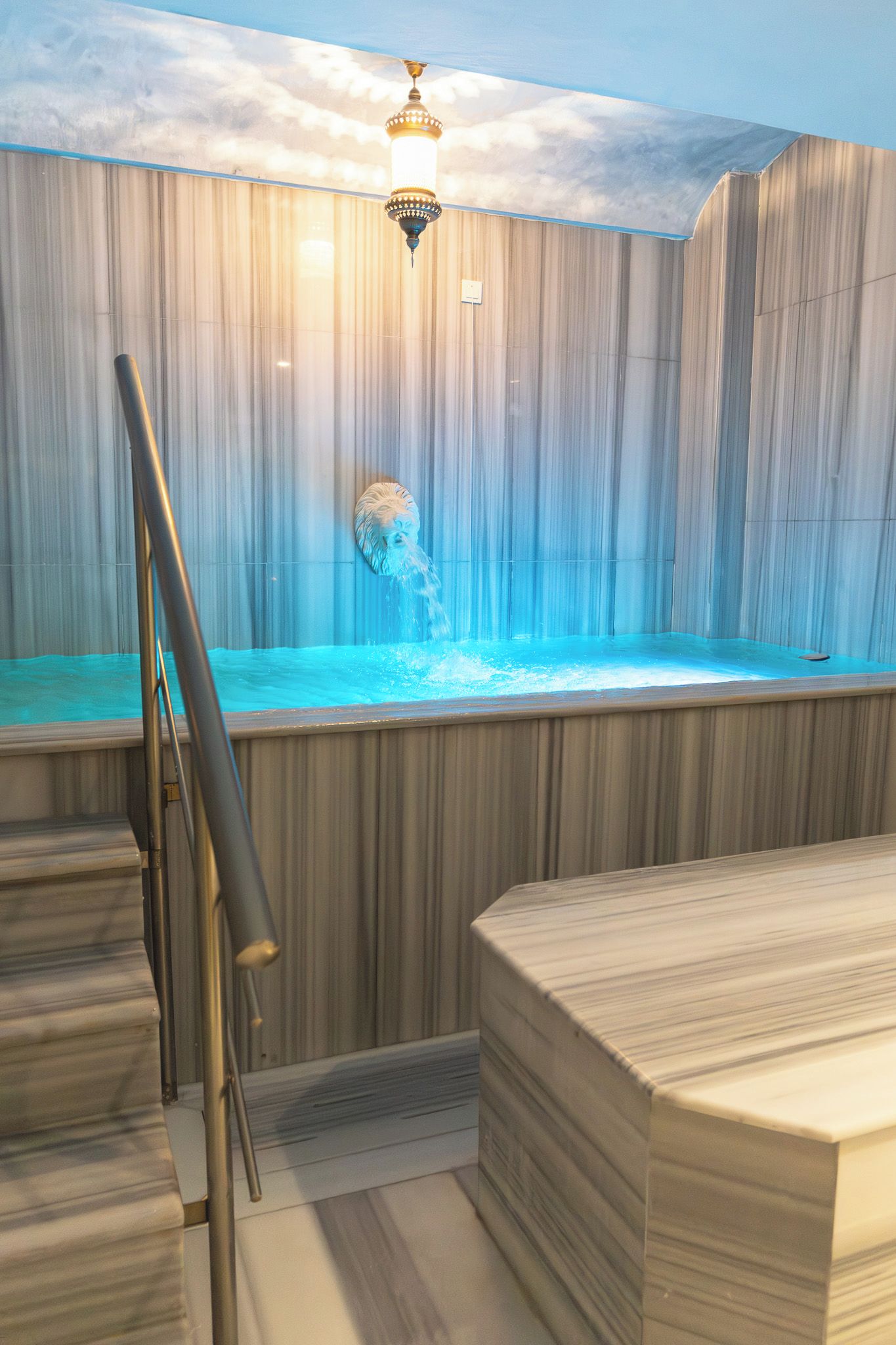 Un jacuzzi con un fondo de pared de madera y una escalera de metal.